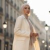 seorang wanita Muslim Indonesia modern (20-an) yang mewakili 'Effortless Elegance'. Dia mengenakan clean hijab pashmina jersey, dipadukan dengan oversized blazer krem dan celana kulot senada.